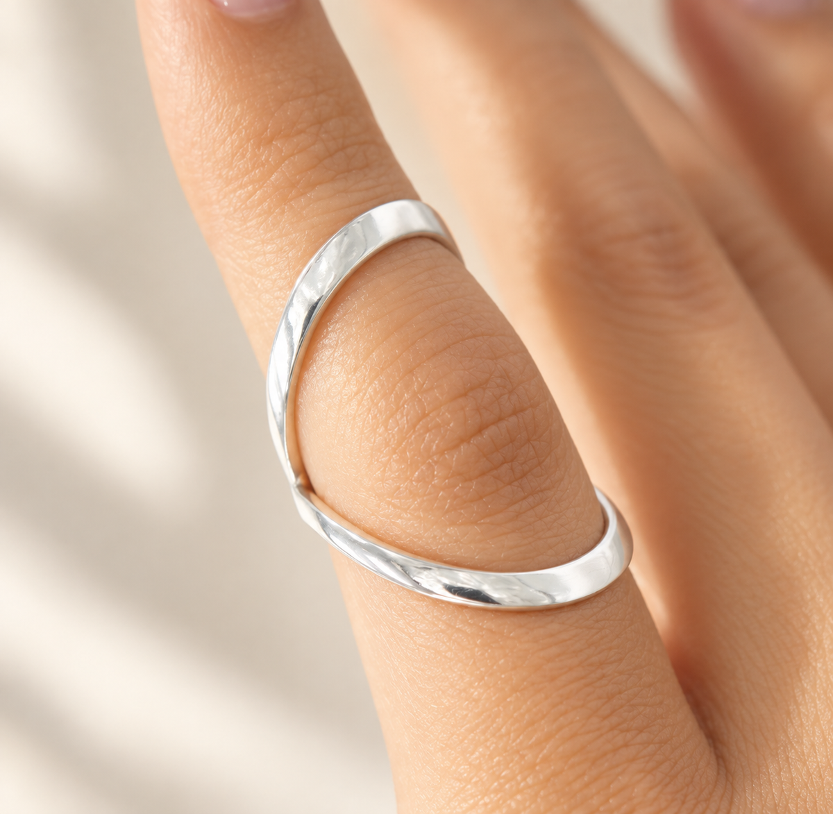 Swan neck splint in polished silver-tone metal worn on a finger, close-up view