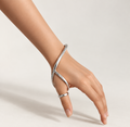 Thumb ring splint with a curved wrist bracelet in polished silver-tone metal, worn on the hand and wrist