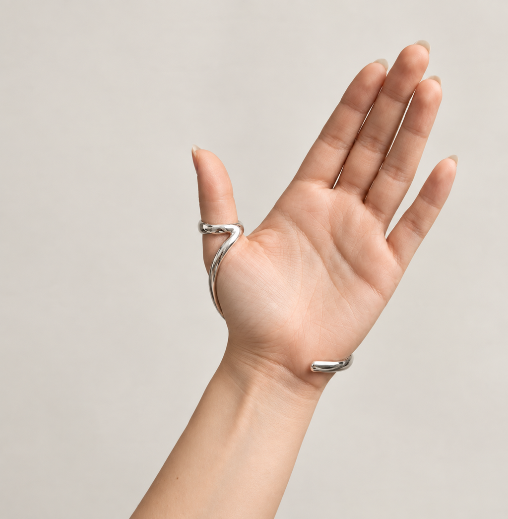 Thumb ring splint and wrist bracelet worn on an open hand, palm view